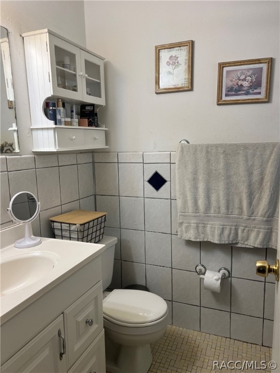 bathroom featuring tile patterned floors, vanity, toilet, and tile walls