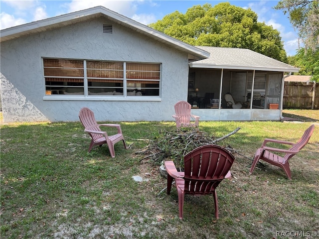 rear view of house featuring a lawn and a sunroom