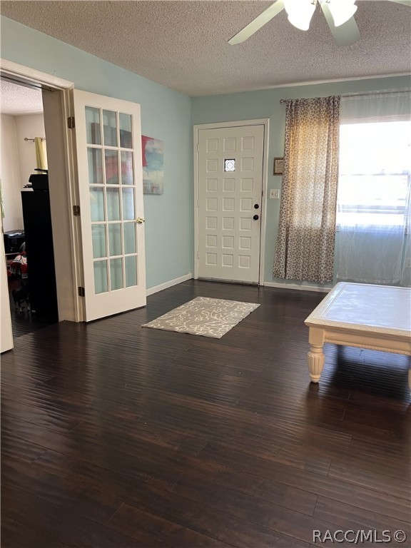 entryway featuring ceiling fan, dark wood-type flooring, and a textured ceiling