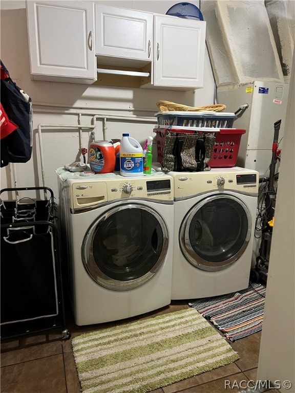 washroom featuring washing machine and dryer, cabinets, and dark tile patterned flooring