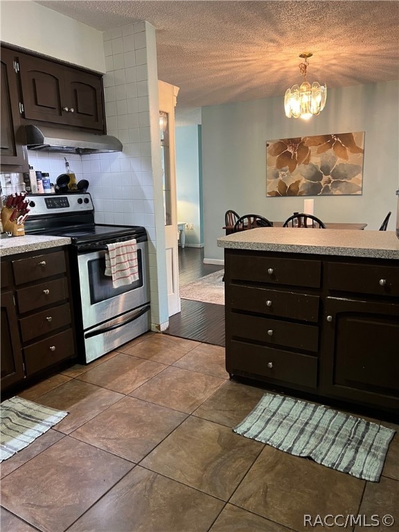 kitchen with dark brown cabinetry, range hood, a chandelier, decorative light fixtures, and stainless steel range with electric cooktop