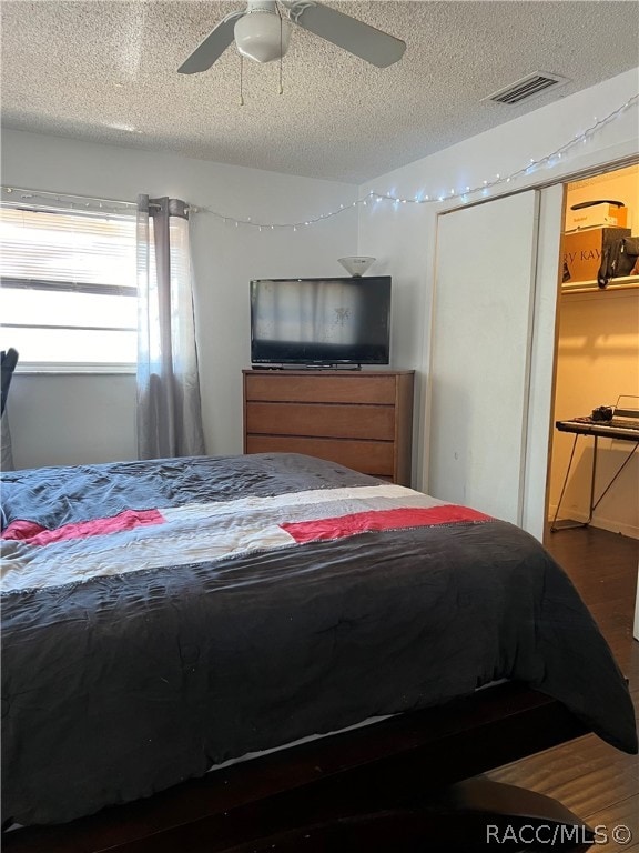 bedroom featuring hardwood / wood-style floors, a textured ceiling, and ceiling fan