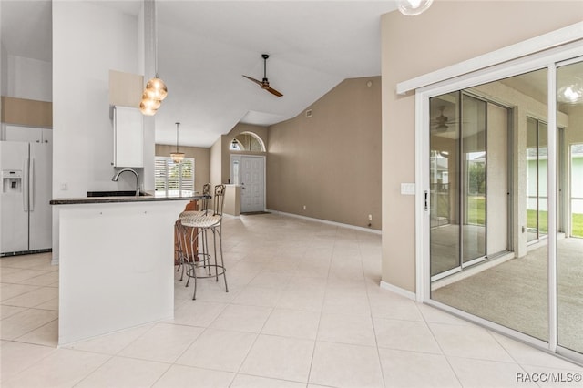 3874 E Lake Todd Dr, Hernando, FL 34442 - kitchen featuring white refrigerator with ice dispenser, a ceiling fan, dark countertops, a breakfast bar, and high vaulted ceiling