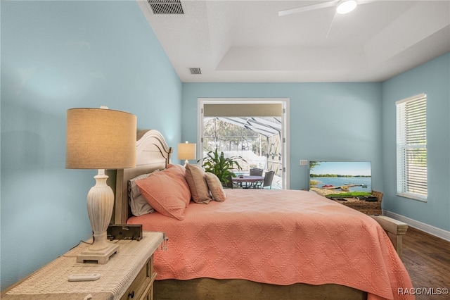 bedroom with a tray ceiling, dark hardwood / wood-style floors, and ceiling fan