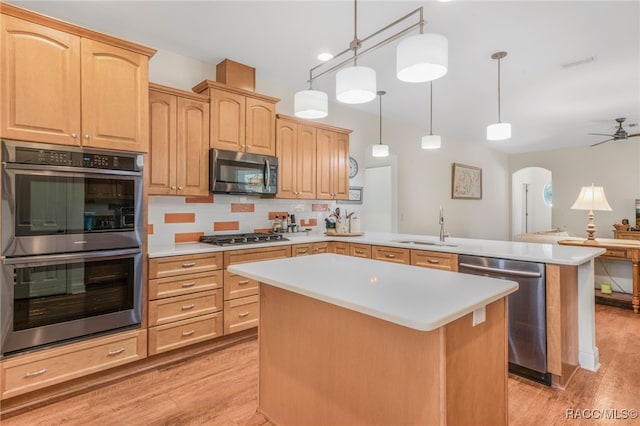 kitchen featuring pendant lighting, sink, a center island, kitchen peninsula, and stainless steel appliances