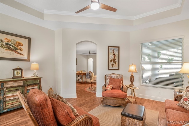 sitting room with ceiling fan, ornamental molding, light wood-type flooring, and a tray ceiling