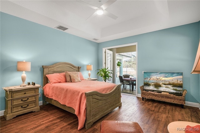 bedroom with ceiling fan, access to outside, dark hardwood / wood-style flooring, and a tray ceiling