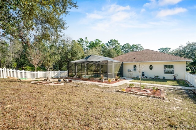 back of property with glass enclosure and a lawn