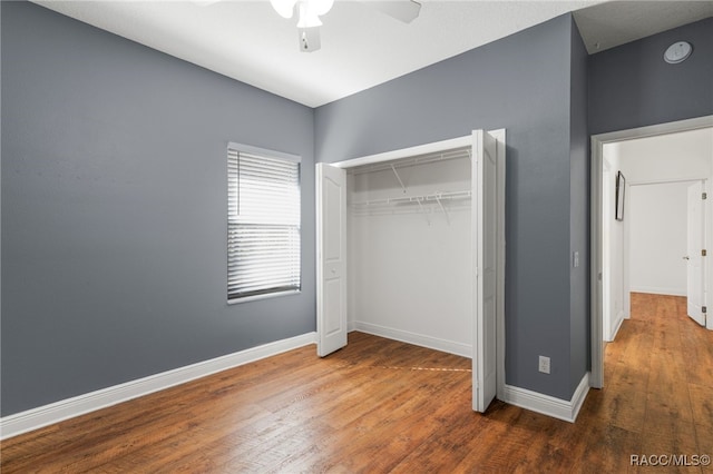 unfurnished bedroom with ceiling fan, dark hardwood / wood-style floors, and a closet