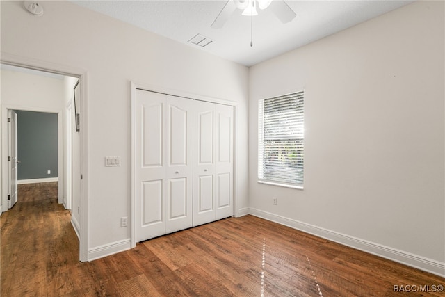 unfurnished bedroom featuring dark wood-type flooring, ceiling fan, and a closet