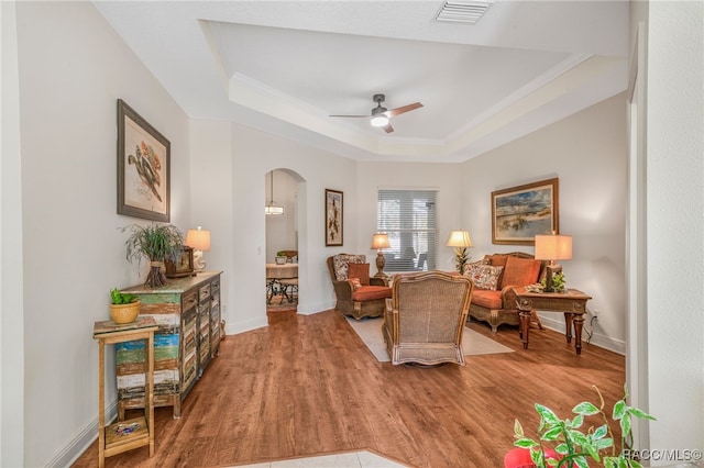 sitting room with ornamental molding, hardwood / wood-style floors, ceiling fan, and a tray ceiling