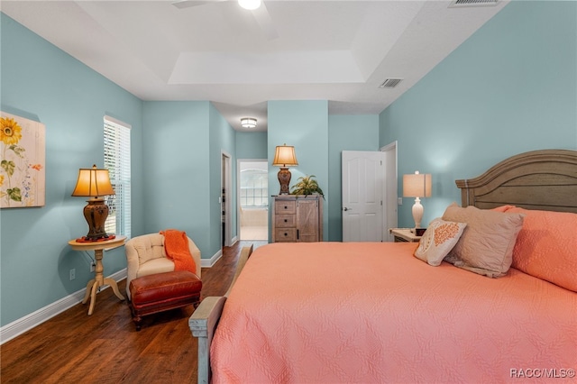 bedroom with ceiling fan, dark hardwood / wood-style flooring, and a tray ceiling