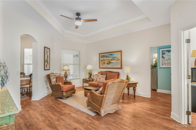 living area featuring ornamental molding, wood-type flooring, and a tray ceiling