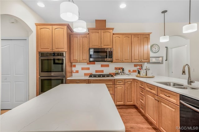 kitchen featuring stainless steel appliances, hanging light fixtures, sink, and light brown cabinetry