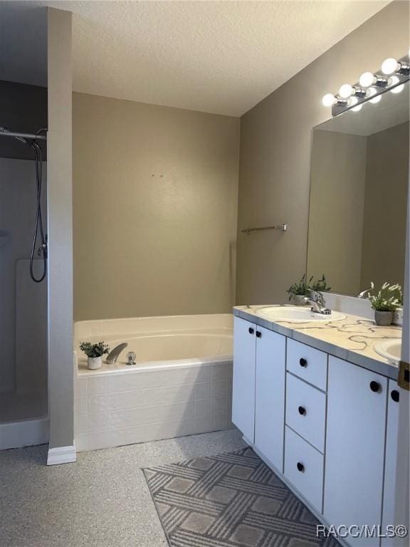 bathroom featuring vanity, independent shower and bath, and a textured ceiling