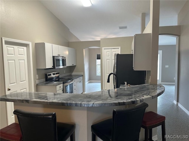 kitchen featuring a breakfast bar, lofted ceiling, and appliances with stainless steel finishes