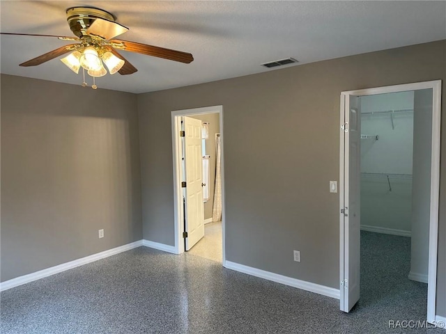 unfurnished bedroom with a closet, a spacious closet, and ceiling fan