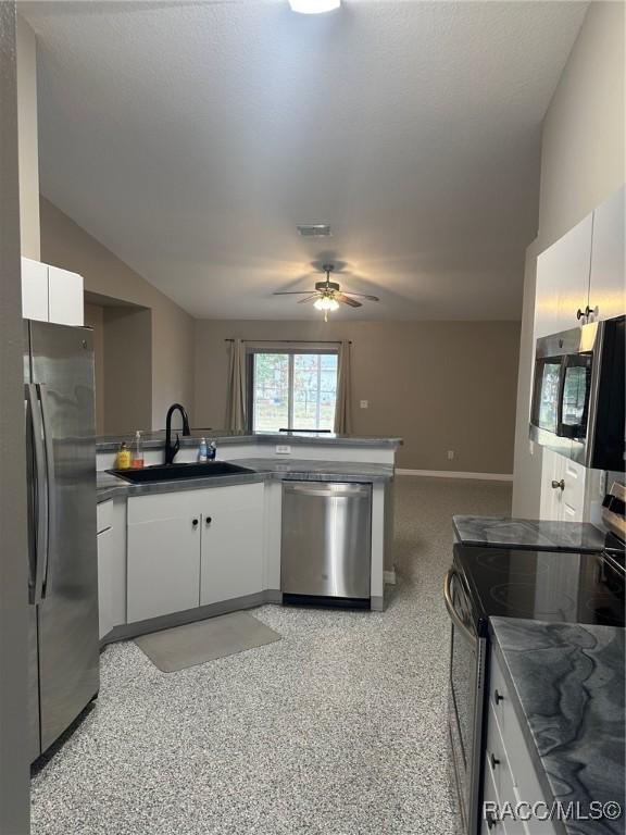 kitchen featuring appliances with stainless steel finishes, vaulted ceiling, ceiling fan, sink, and white cabinets