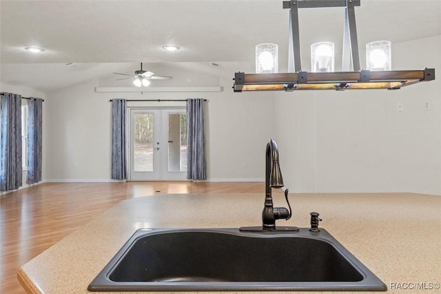 kitchen with lofted ceiling, a sink, light wood-style floors, light countertops, and french doors