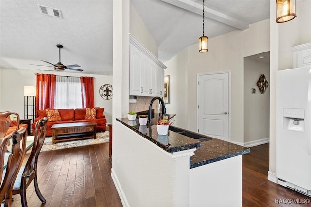 kitchen featuring visible vents, dark wood finished floors, decorative light fixtures, white fridge with ice dispenser, and white cabinetry