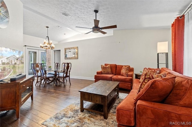 living room with a textured ceiling, dark wood-style flooring, visible vents, baseboards, and vaulted ceiling