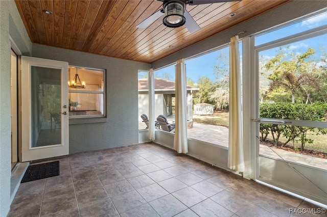 unfurnished sunroom featuring a ceiling fan, wooden ceiling, and a healthy amount of sunlight