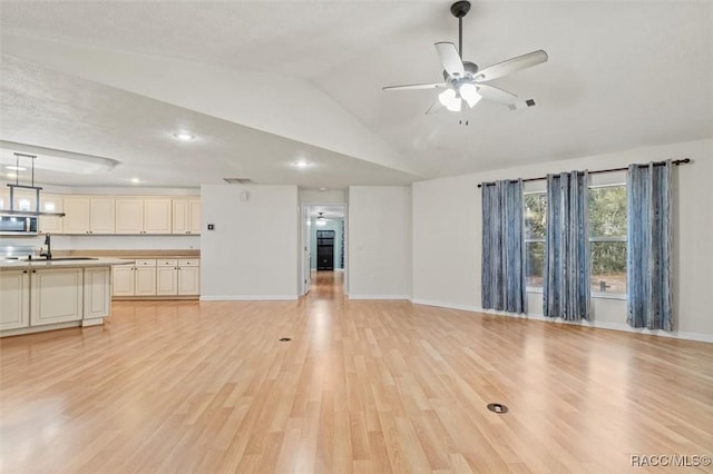 unfurnished living room with a ceiling fan, visible vents, vaulted ceiling, and light wood-style flooring