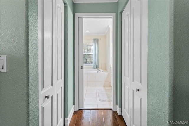 hall with ornamental molding, a textured wall, and dark wood-type flooring