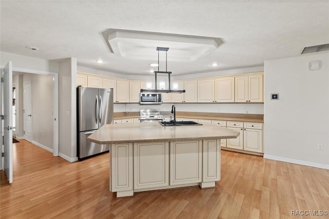 kitchen with stainless steel appliances, light countertops, a center island with sink, and pendant lighting