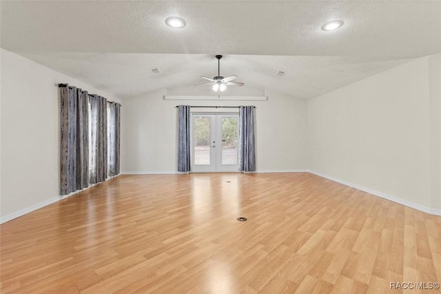 empty room featuring lofted ceiling, ceiling fan, a textured ceiling, light wood-style floors, and french doors