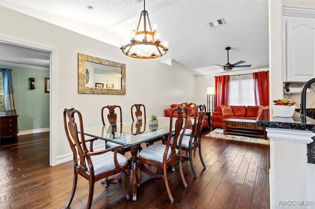 dining room with a textured ceiling, ceiling fan with notable chandelier, dark wood-style flooring, visible vents, and baseboards