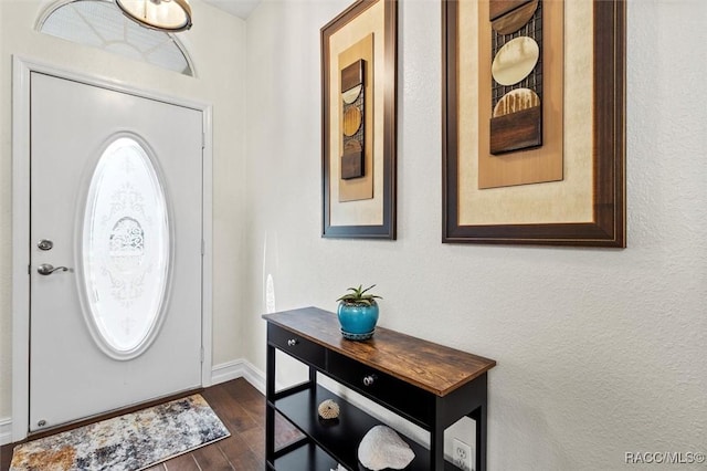 foyer entrance featuring dark wood-type flooring and baseboards