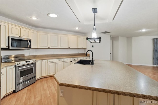 kitchen with appliances with stainless steel finishes, a kitchen island with sink, a sink, and cream cabinets