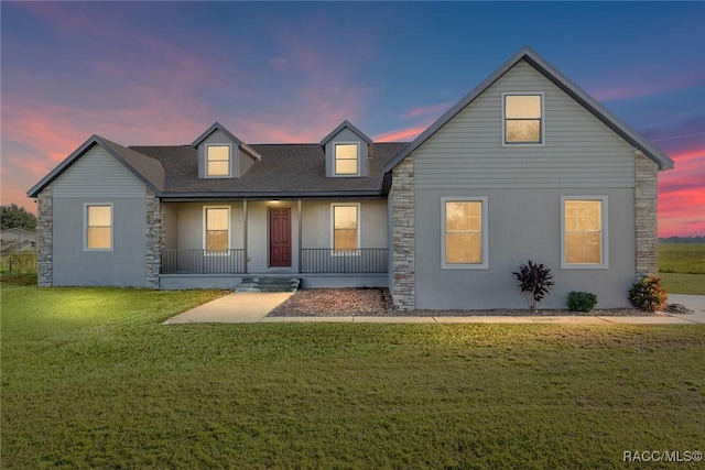 back house at dusk with a lawn and covered porch