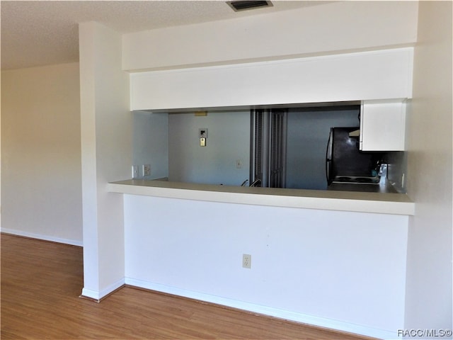 kitchen featuring hardwood / wood-style floors, black range, and a textured ceiling