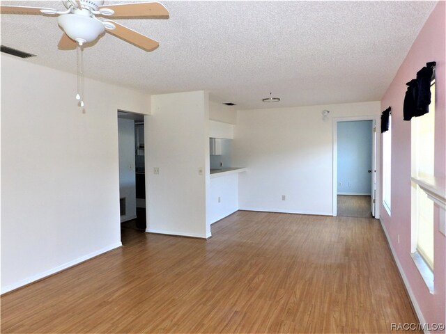 unfurnished living room featuring ceiling fan, a textured ceiling, and hardwood / wood-style flooring