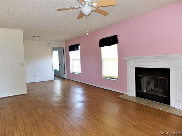 unfurnished living room with hardwood / wood-style floors, ceiling fan, and a textured ceiling