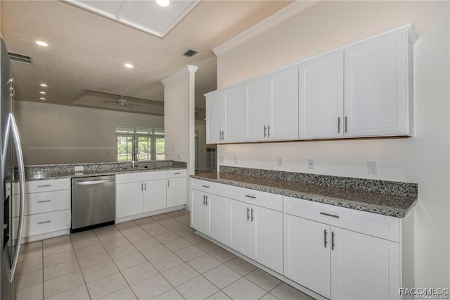 kitchen with ceiling fan, dark stone countertops, appliances with stainless steel finishes, light tile patterned flooring, and white cabinetry