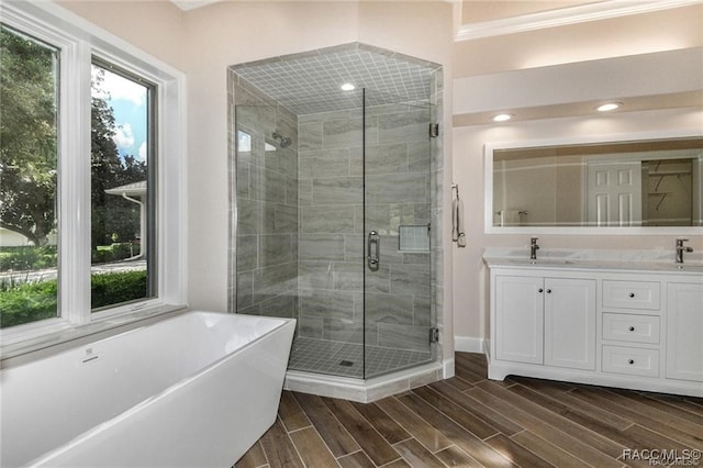 bathroom with vanity, wood-type flooring, crown molding, and plus walk in shower