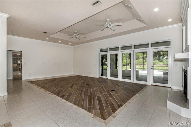 living room with a tray ceiling, ceiling fan, light wood-type flooring, and ornamental molding