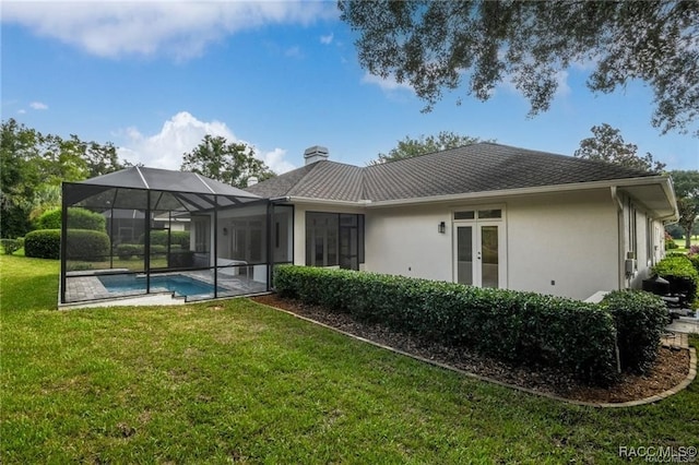 rear view of property featuring a lanai, french doors, and a lawn