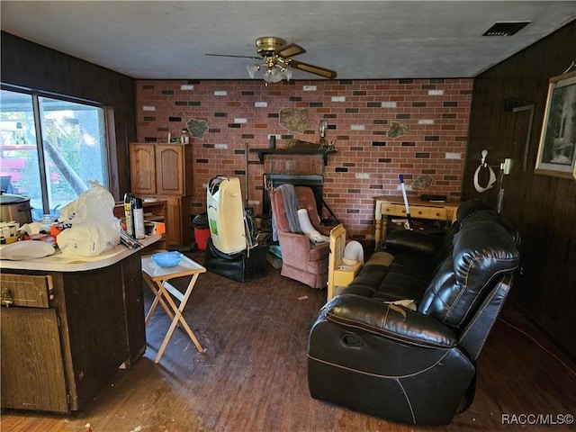 living room with dark hardwood / wood-style floors, wood walls, brick wall, and ceiling fan