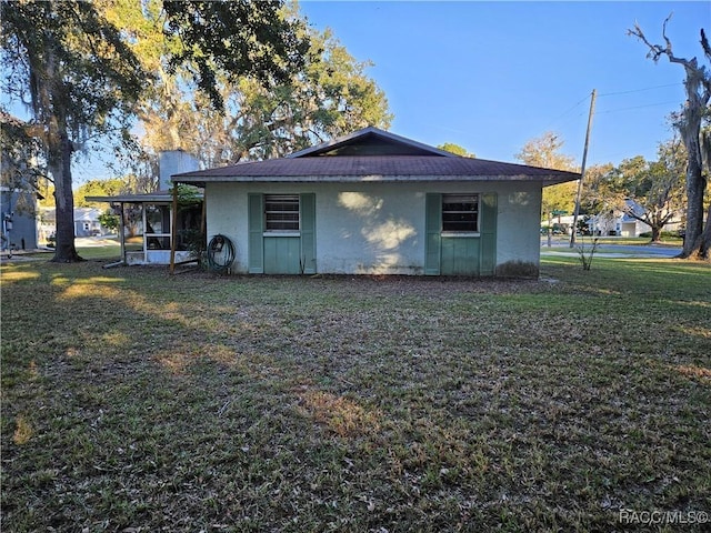 view of side of property featuring a lawn and a sunroom