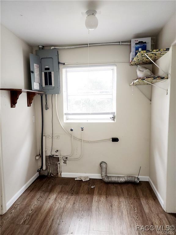 laundry area featuring laundry area, electric panel, baseboards, and wood finished floors