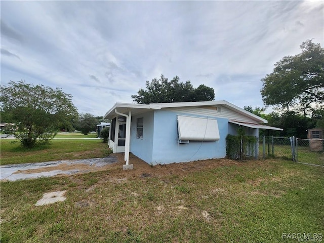 view of property exterior featuring a yard, fence, a gate, and stucco siding