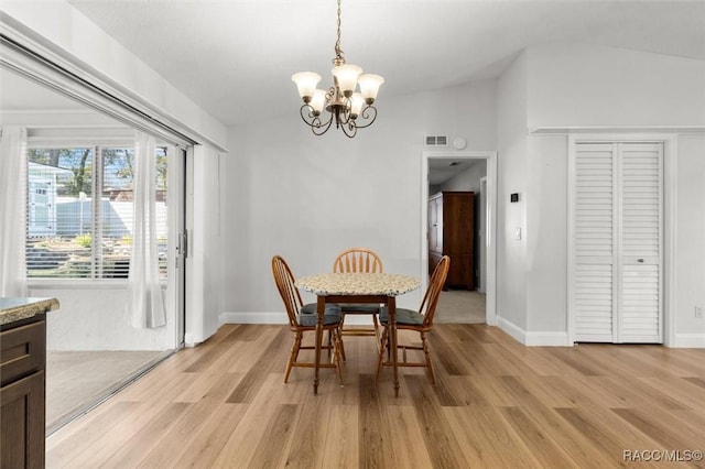 dining room with light wood-type flooring, visible vents, a notable chandelier, and lofted ceiling