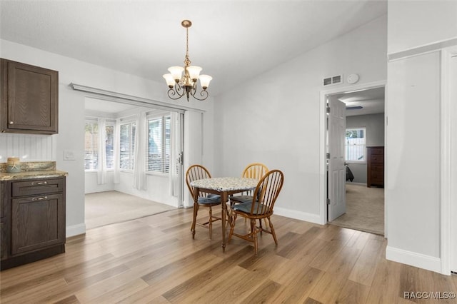 dining area featuring baseboards, light wood-style flooring, visible vents, and a notable chandelier