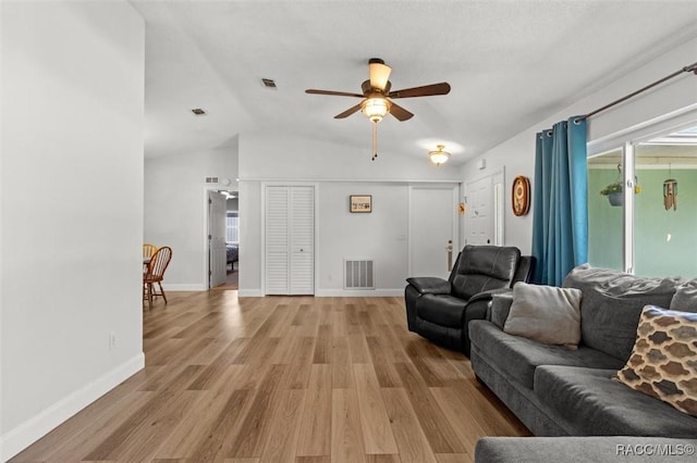 living area featuring light wood-type flooring, baseboards, visible vents, and lofted ceiling