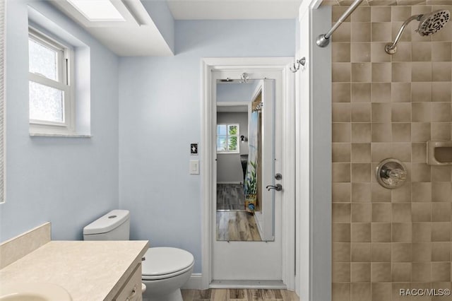 bathroom featuring tiled shower, vanity, toilet, and wood finished floors