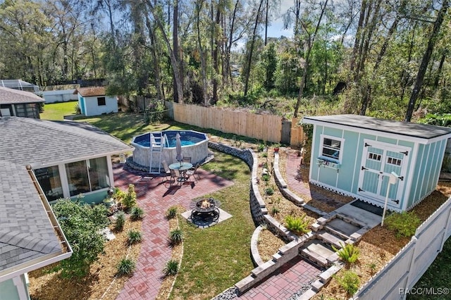 view of yard with an outdoor fire pit, a patio area, a fenced backyard, and a storage unit